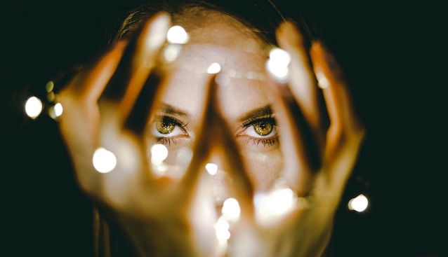 woman looking through fairy lights
