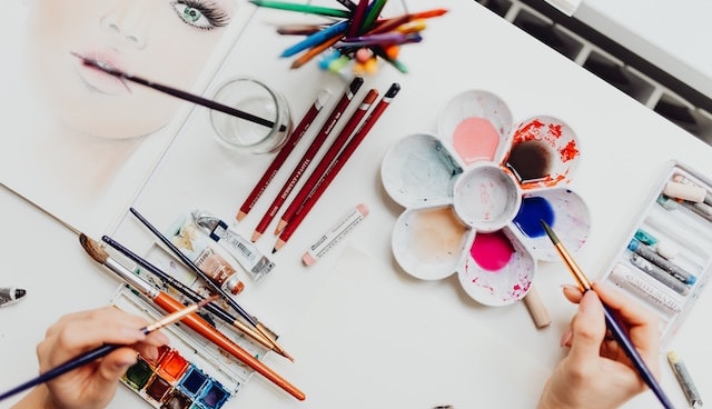 hands using many brushed to paint watercolour painting of a woman's face